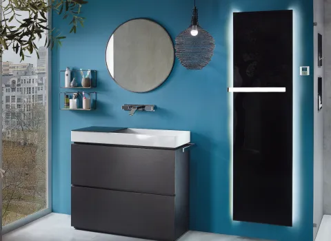 Schwarzer Badheizkörper Plawa von Bemm vor einer blauen Wand neben einem Waschplatz im Badezimmer. 