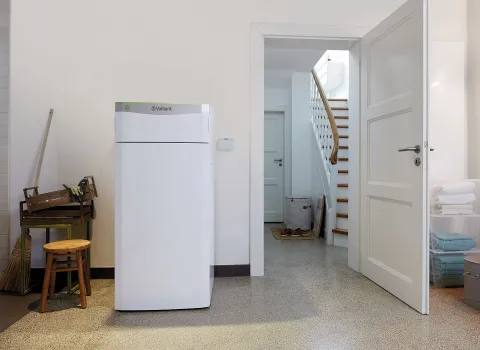 Eine Vaillant-Innenwärmepumpe steht in einem Hauswirtschaftsraum mit Zugang zu einer offenen Treppe.