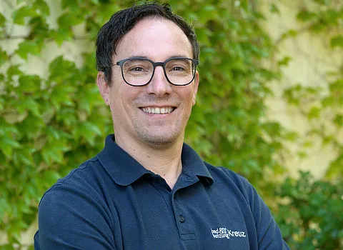 Ein Mitarbeiter der Kreuz GmbH im dunklen Hemd lächelt in die Kamera.