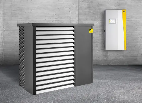 Außen- und Inneneinheit der Wärmepumpe AERO ALM 6-15 in einem grauen Lagerraum.