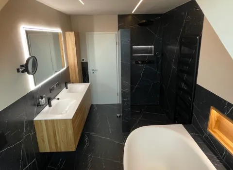 Modernes Badezimmer mit dunklen Marmoroptik-Fliesen in Schwarz, freistehender Badewanne und begehbarer Dusche.