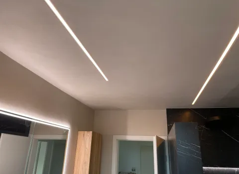 Moderne Beleuchtung in Badezimmer mit Leuchtspiegel und Fliesen in Marmoroptik.