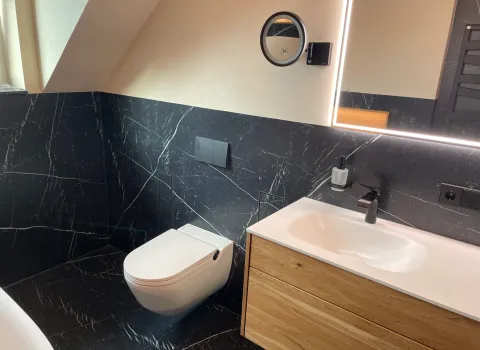 Ein Dusch-WC in einem modernen Badezimmer mit dunklen Fliesen in Marmoroptik.