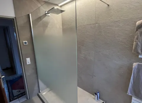 Walk-In-Dusche mit Regendusche und LED-Beleuchtungsstreifen.