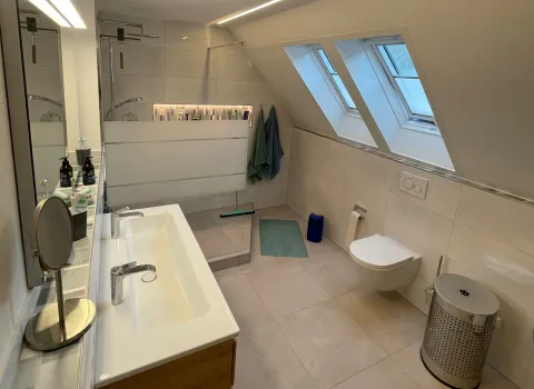 Renoviertes Badezimmer mit Dachschräge, Waschtisch und WC in modernem Design.