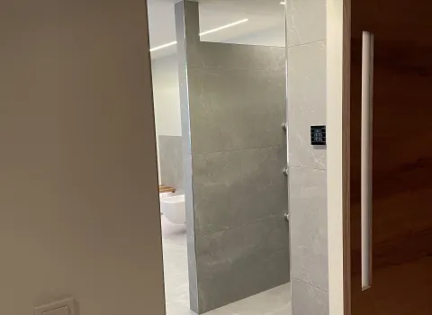 Blick in modernes Badezimmer mit grauen Fliesen und offener Raumgestaltung.