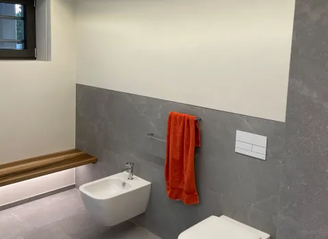 Modernes WC und Bidet mit Holzbank und indirekter LED-Beleuchtung.