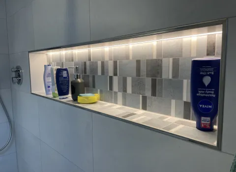 Geflieste Dusch-Nische mit LED-Beleuchtung und integrierter Ablage.