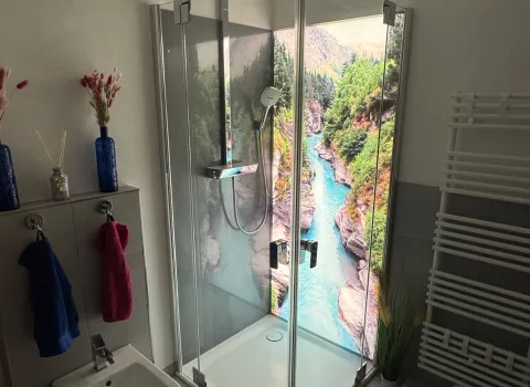 Moderne Eckdusche mit Glas und dekorativer Naturbild-Rückwand.