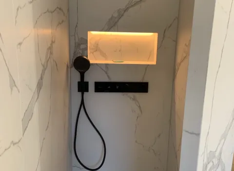 Moderne Dusche mit Regendusche und indirekt beleuchteter Ablagenische.