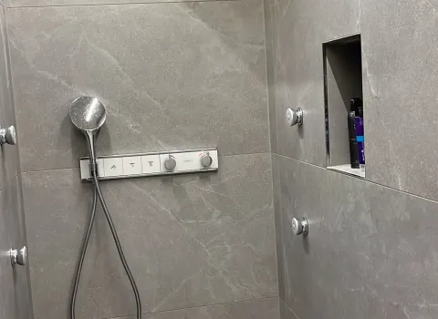Moderne Dusche mit Regendusche, grauen Großformatfliesen und integrierter Nische.
