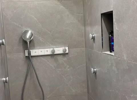 Moderne Dusche mit Regendusche, grauen Großformatfliesen und integrierter Nische.
