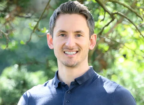 Portrait des Geschäftsführers Florian Goerke vor grünen Blättern.