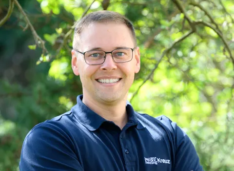 Ein Mitarbeiter der Kreuz GmbH im dunklen Hemd und Brille lächelt in die Kamera.