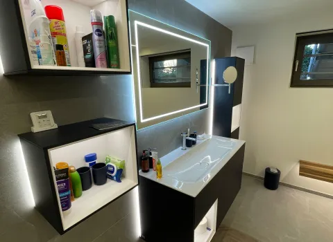 Schwarzer Waschtisch mit LED-Spiegel und modernem Badezimmerdesign.